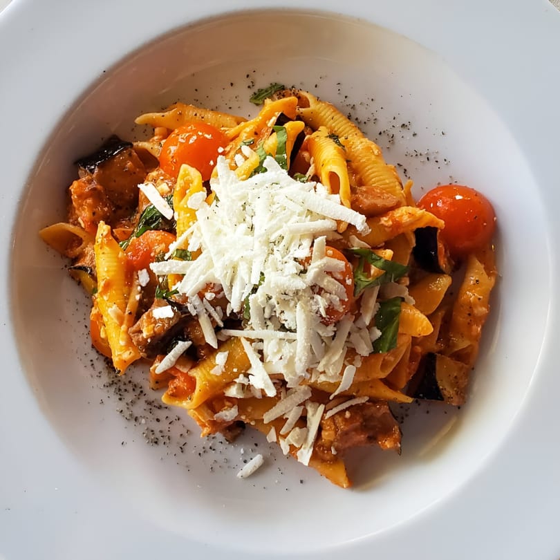 Tommy V's Italian pasta dish with shell pasta, cherry tomatoes, eggplant, and shredded cheese.