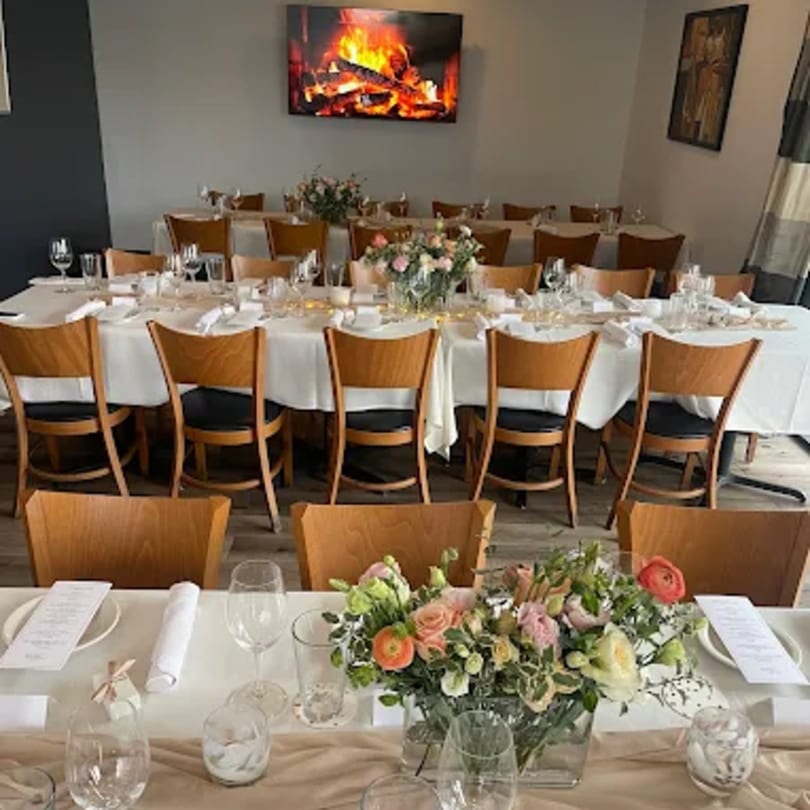 Dining room at Tommy V's Urban Kitchen & Bar with set tables, floral centerpieces, and a fireplace screen.