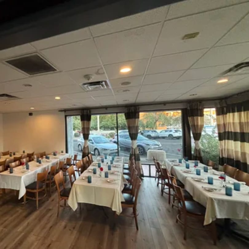 Dining room at Tommy V's Urban Kitchen & Bar with long tables set for guests and large windows.
