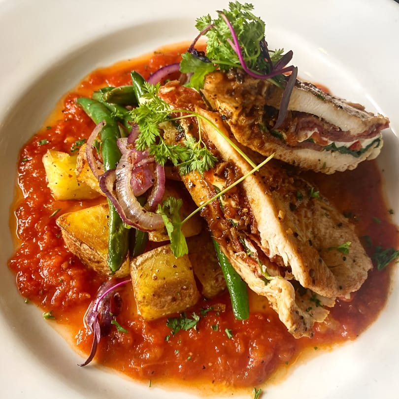 Italian chicken dish with tomato sauce, roasted potatoes, green beans, and red onions.